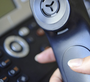 Hand hält schwarzen Telefonhörer.